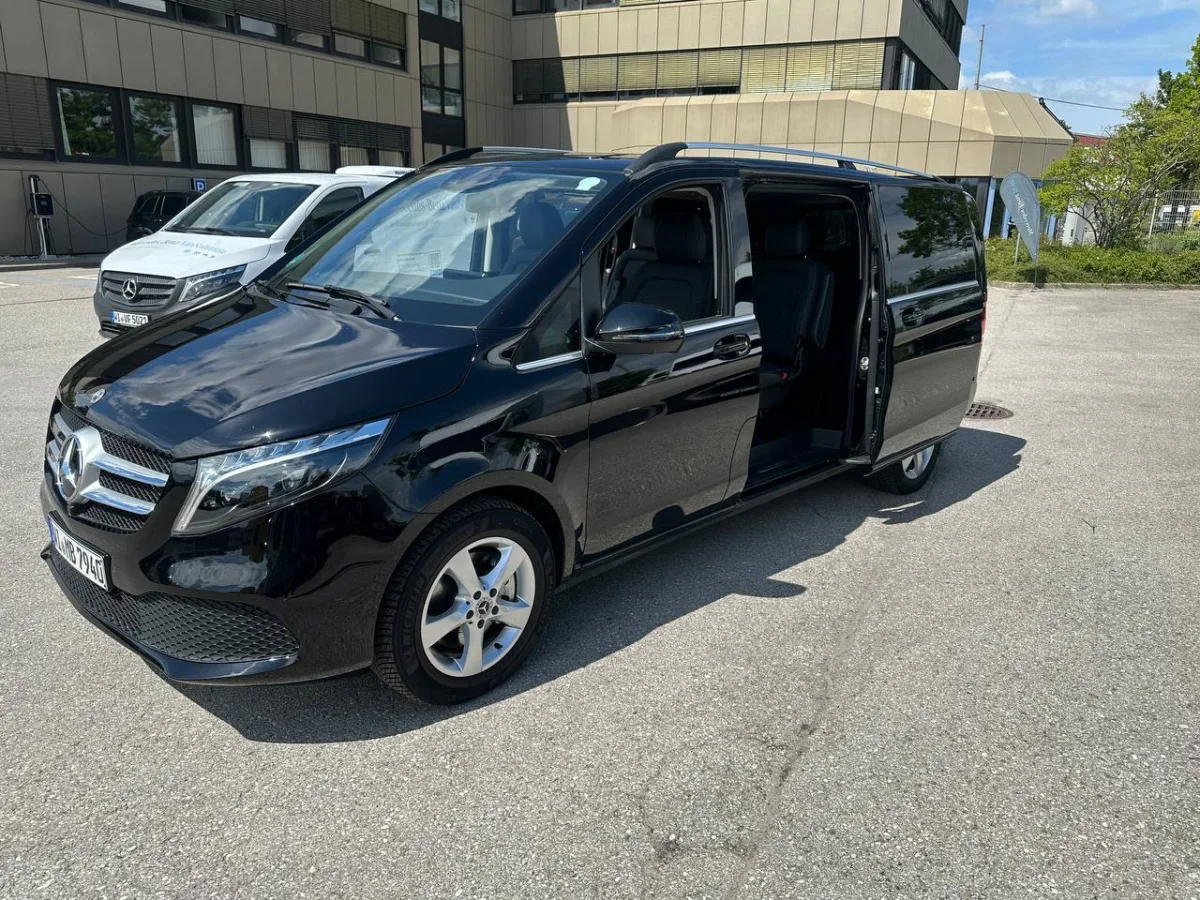 Black Mercedes 8-seater V-Class passenger van with the sliding side door open, showing rear passenger seating and cargo space