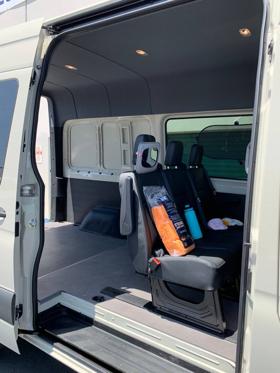 Sliding side door open on the crew cargo Sprinter, showing the rear bench seat and the cargo area behind it