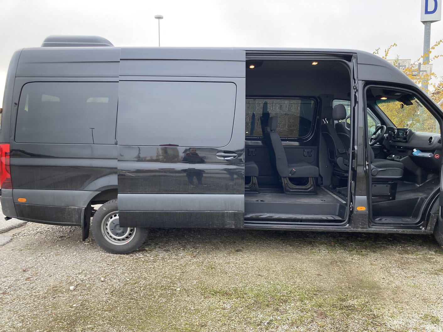 Side view of the 9 passenger Mercedes-Benz Sprinter van with the sliding door and driver door open