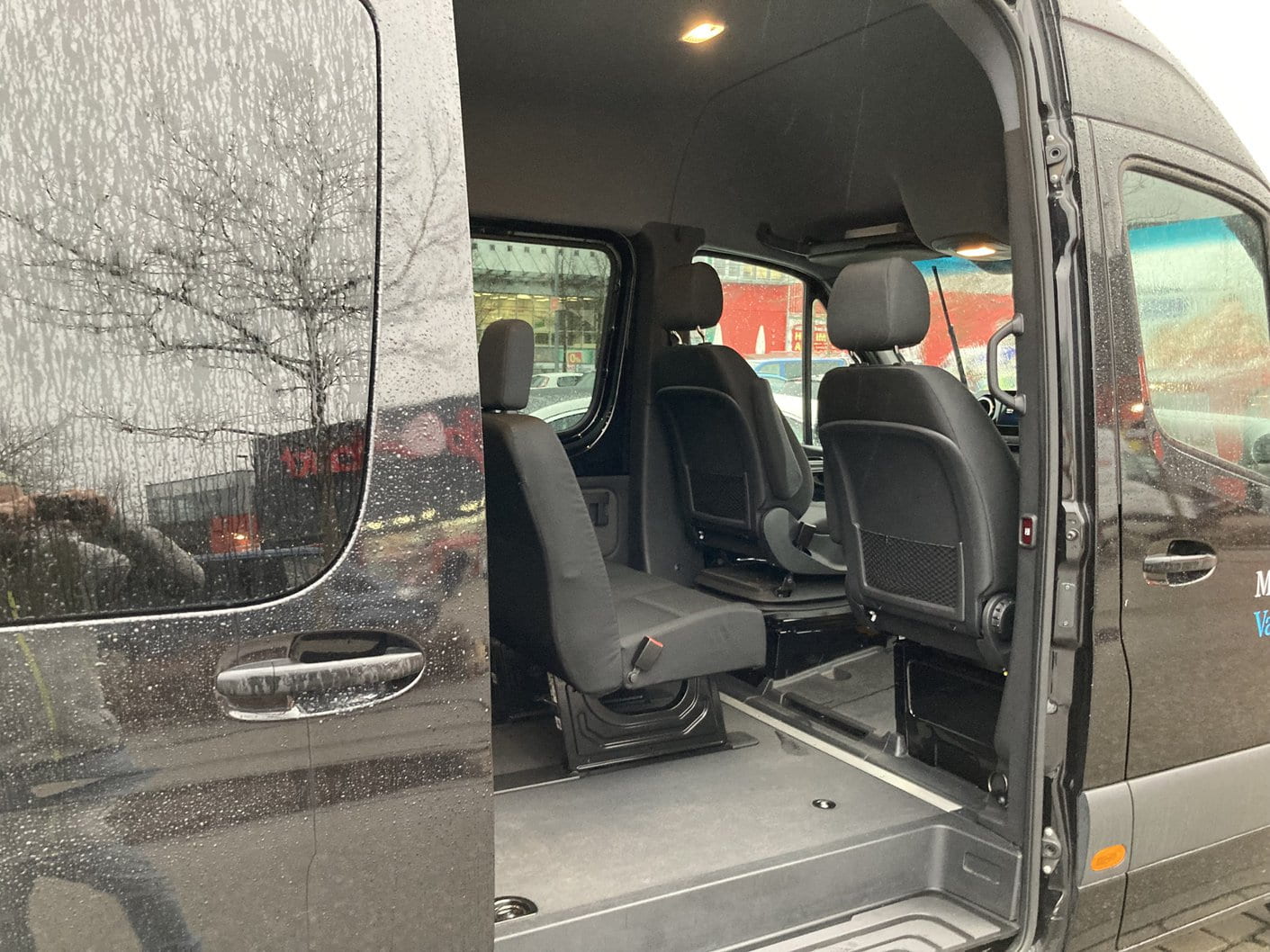 Sliding side door open on the 9 passenger Sprinter van, showing the second-row seats