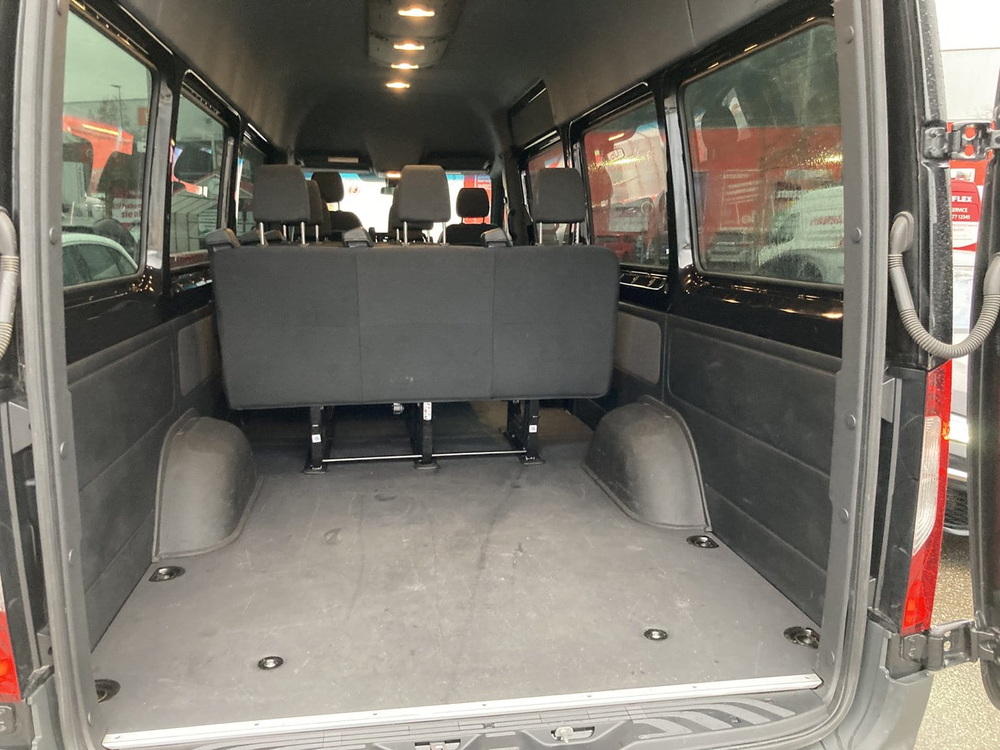 Cargo space behind the last bench of the 9 seater Sprinter van, seen through the open rear doors