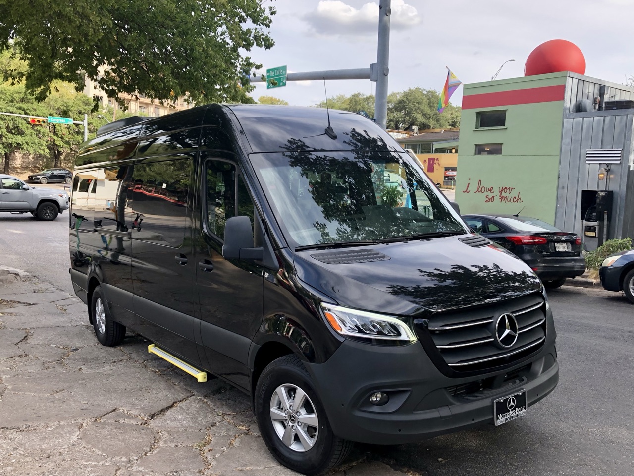 Black Mercedes-Benz Sprinter passenger van for rent in Austin, TX — front three-quarter view near downtown Austin