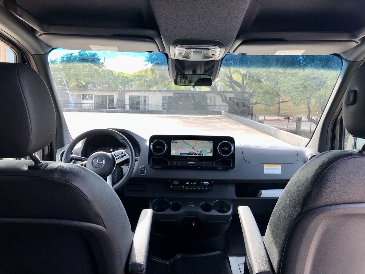 Sprinter van cockpit with Mercedes steering wheel, digital navigation display, and dual climate control — Austin rental fleet