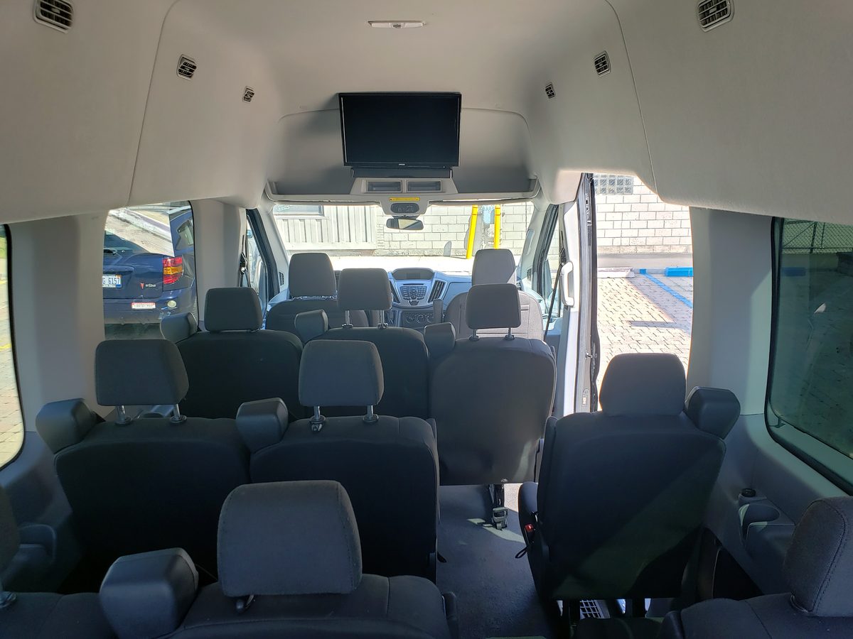 Interior seating rows of a high roof Ford Transit 15-passenger van available to rent in Detroit Michigan