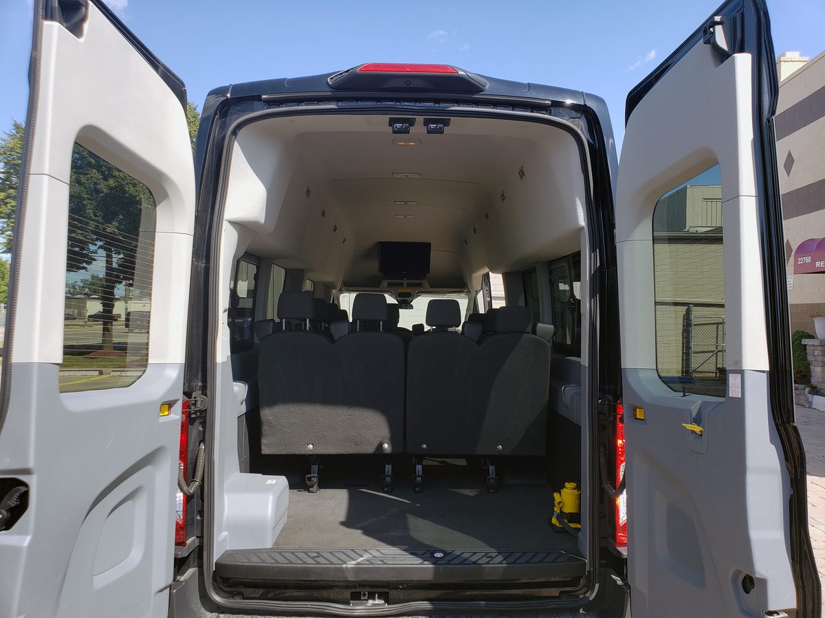 Ford Transit passenger van with rear doors open showing trunk space behind the back row — Detroit van rental with luggage room