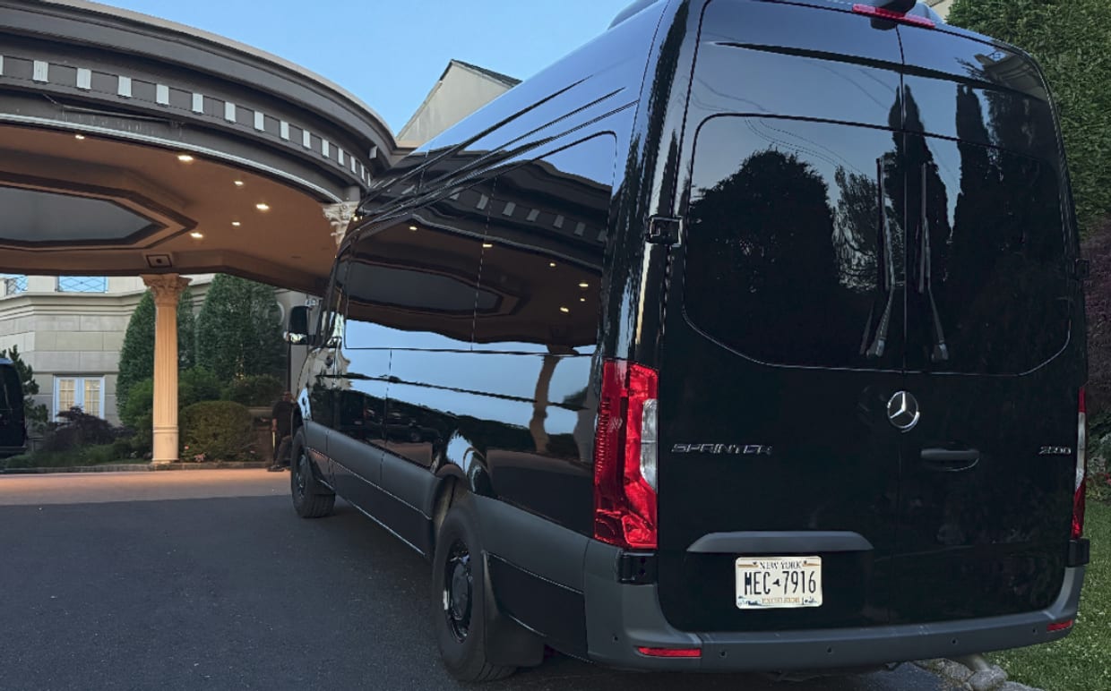 Black Mercedes-Benz Sprinter high roof passenger van with New York plates parked at an estate entrance — Sprinter Rentals New York van rental