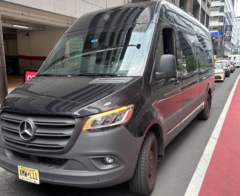 Black Mercedes-Benz Sprinter passenger van for rent parked on a New York City street