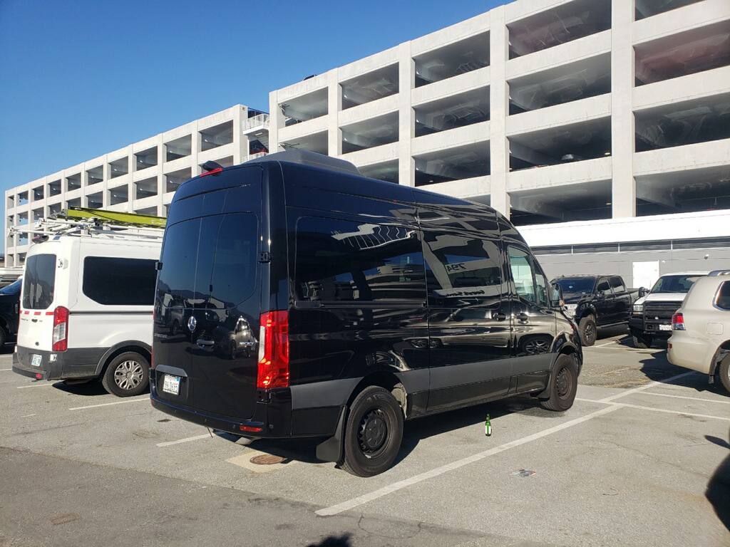 Black Mercedes-Benz Sprinter passenger van rear view at airport parking garage — Sacramento van rental near SMF