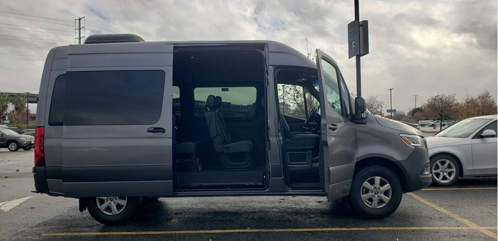 Mercedes-Benz Sprinter passenger van with sliding side door open showing seating — Sacramento van rental fleet