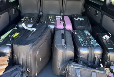 The cargo space of a 12-passenger Mercedes-Benz Sprinter van, shown with bags and luggage inside