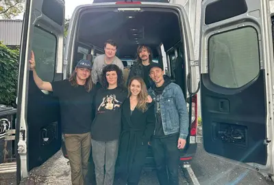 A group standing beside a rented 15-passenger Mercedes-Benz Sprinter van